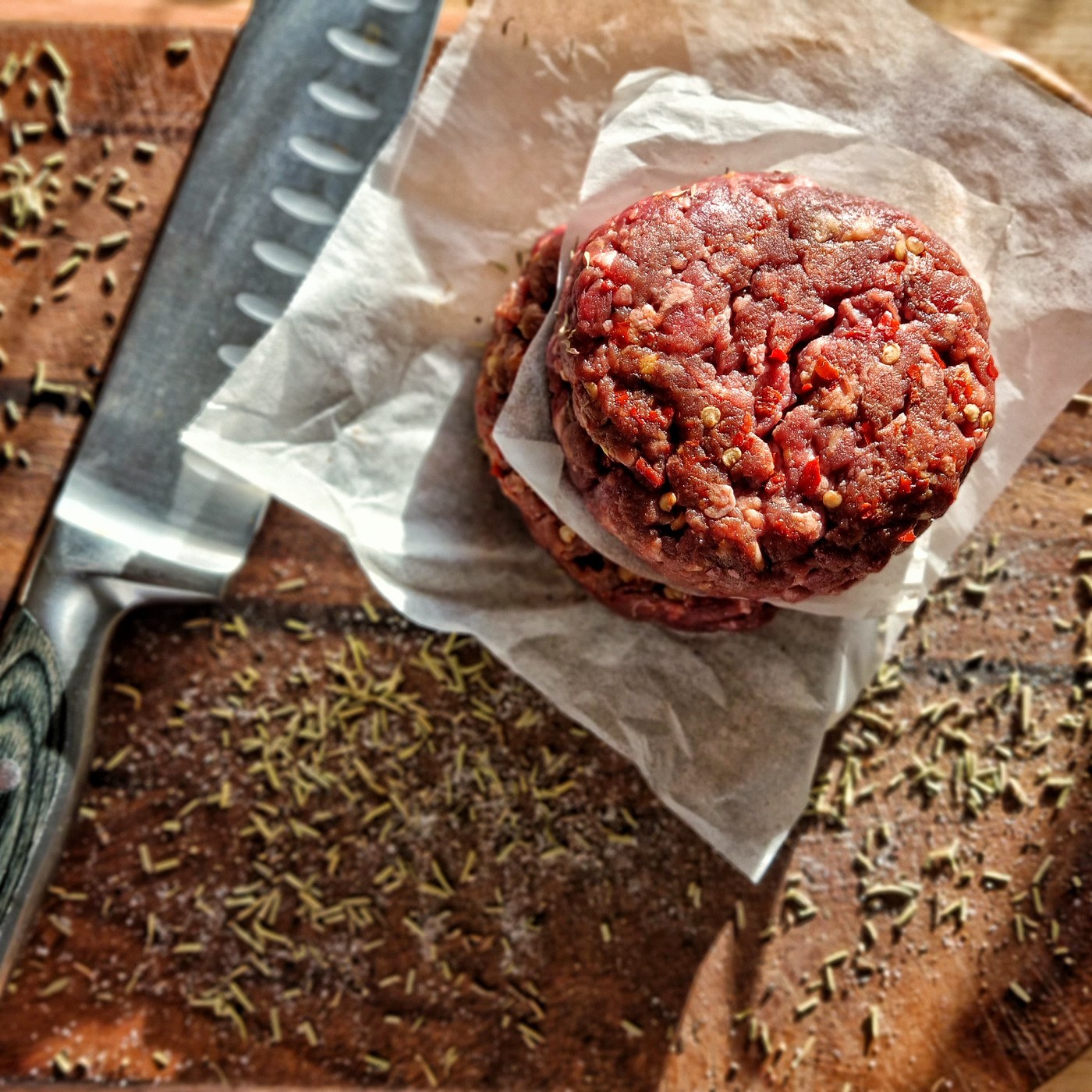 Seasoned burger preparations arranged on a pale surface